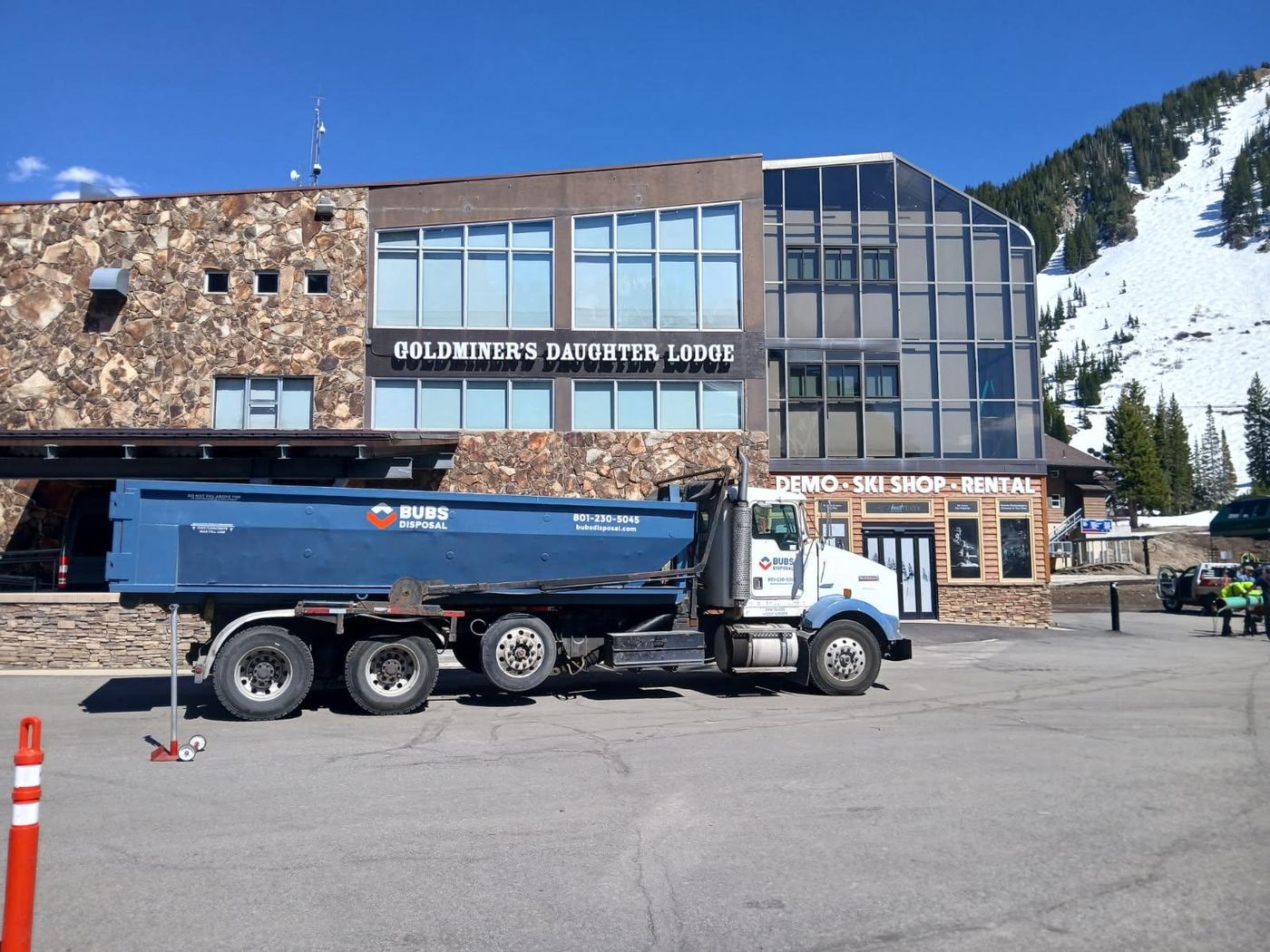 Bubs truck delivering a dumpster in Alta, Little Cottonwood Canyon, with the ski slopes behind